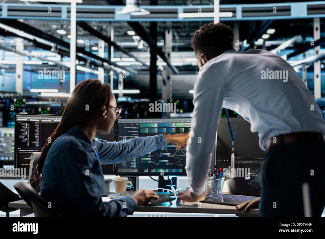 Data center technician team oversees machine learning system setup, guiding an engineer and neural network training for server operations. Stock Photo