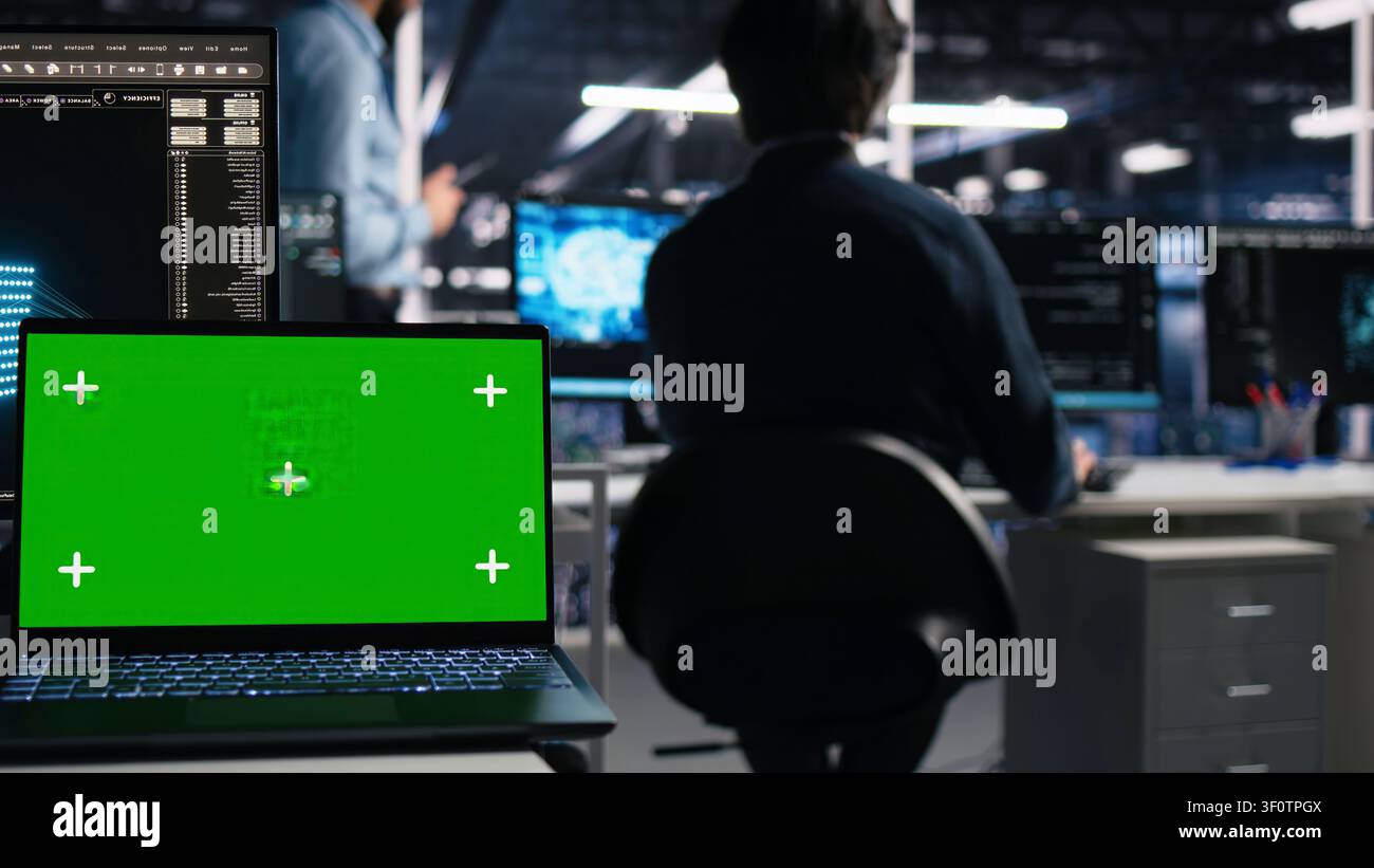 Software developer uses a green screen laptop to manage AI systems, machine learning workflows and server performance. Stock Photo