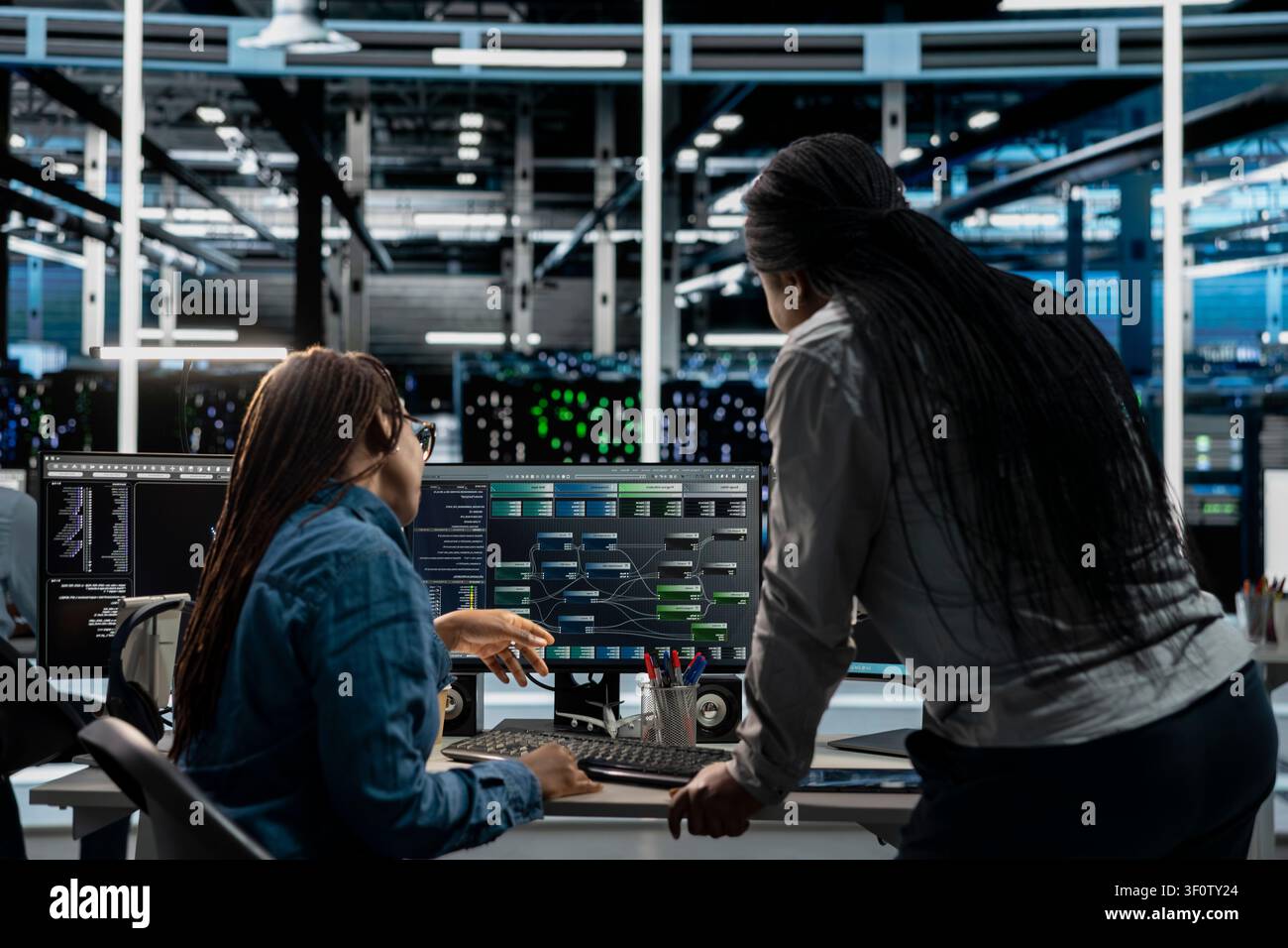 Data center supervisor supervising technical work from systems engineer applying AI to reduce downtime. Stock Photo