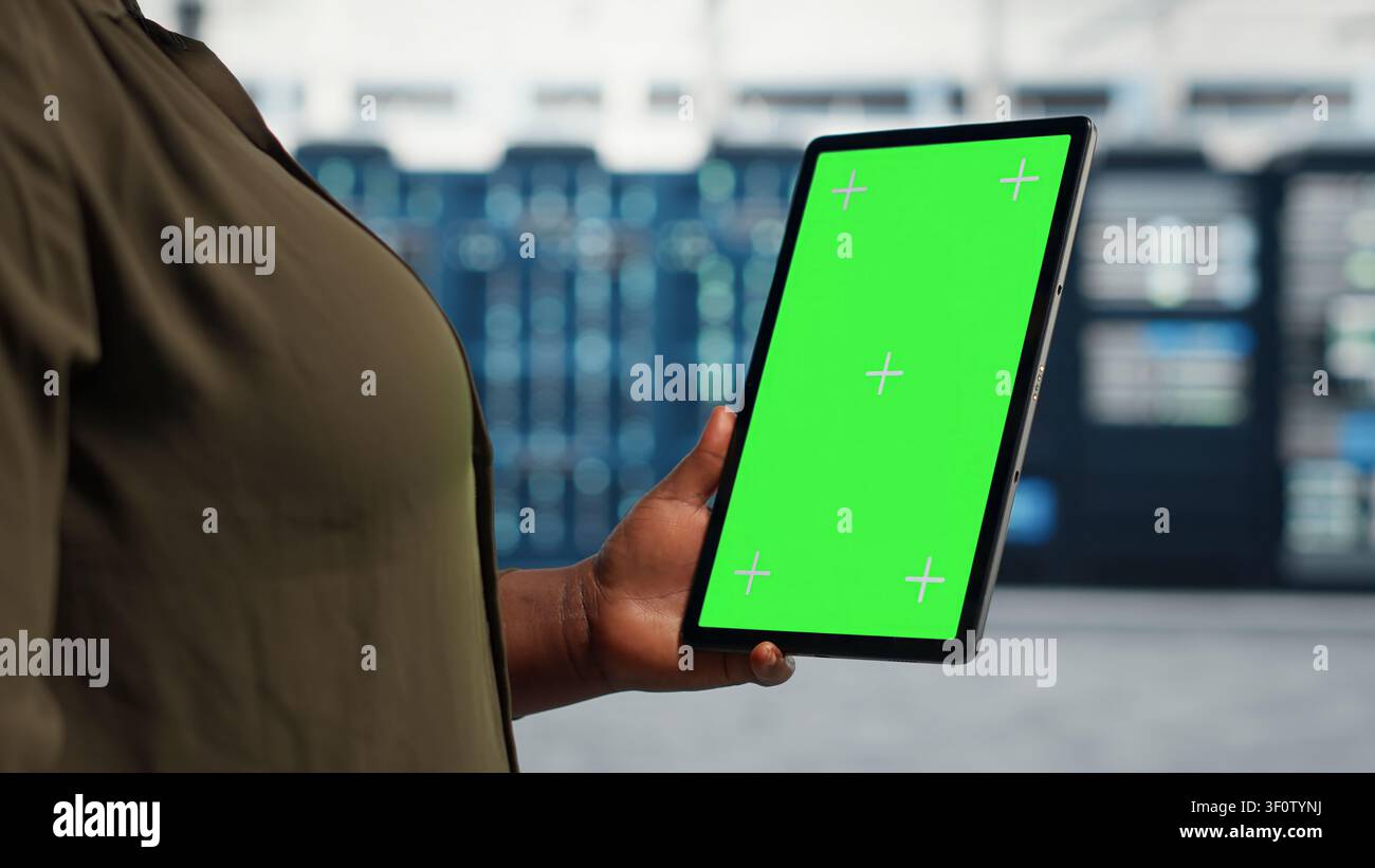 Data center administrator works with a chroma key tablet, using an editable screen to expand workload capacity. Stock Photo