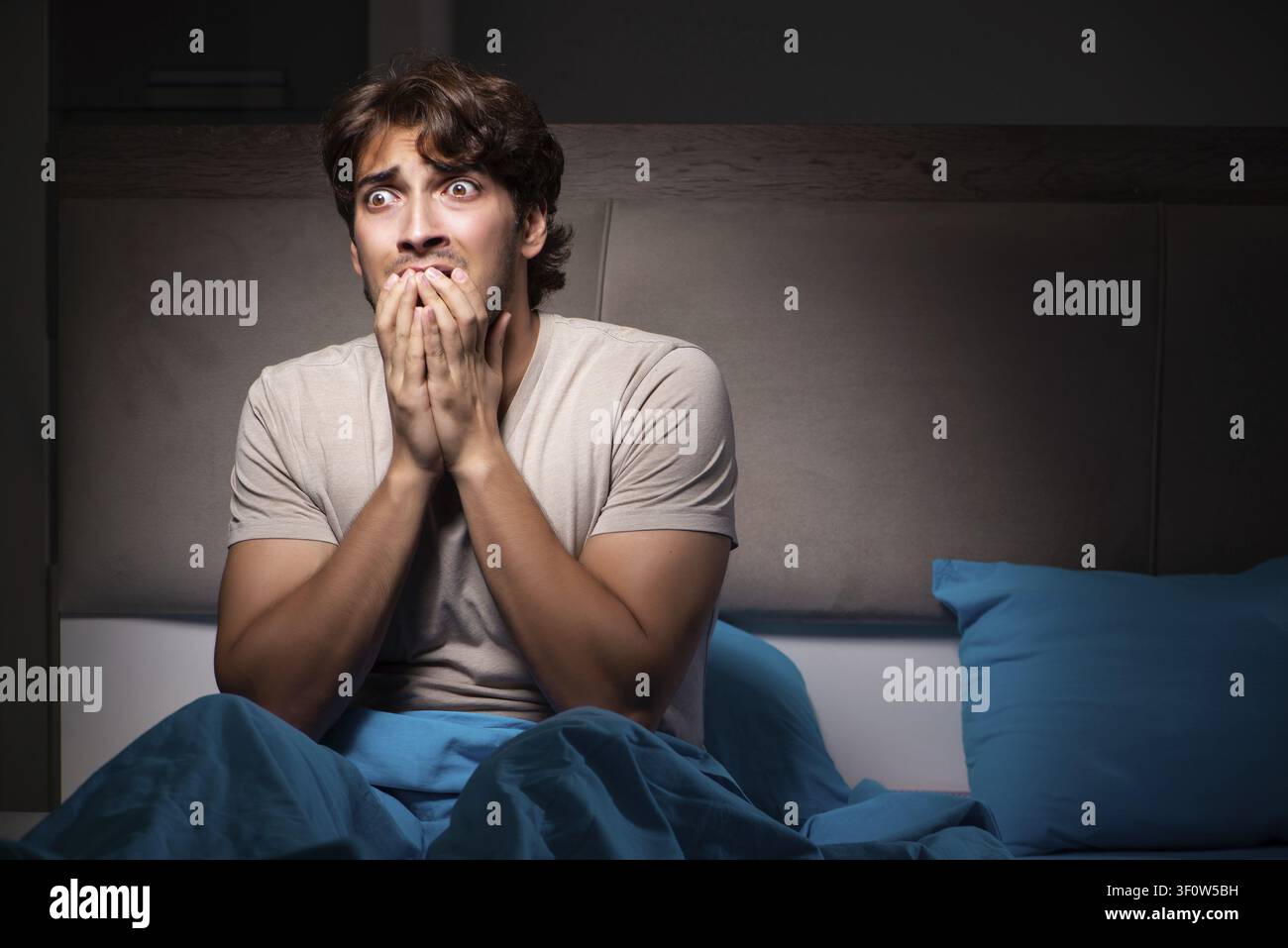 Young man scared in his bed having nightmares Stock Photo
