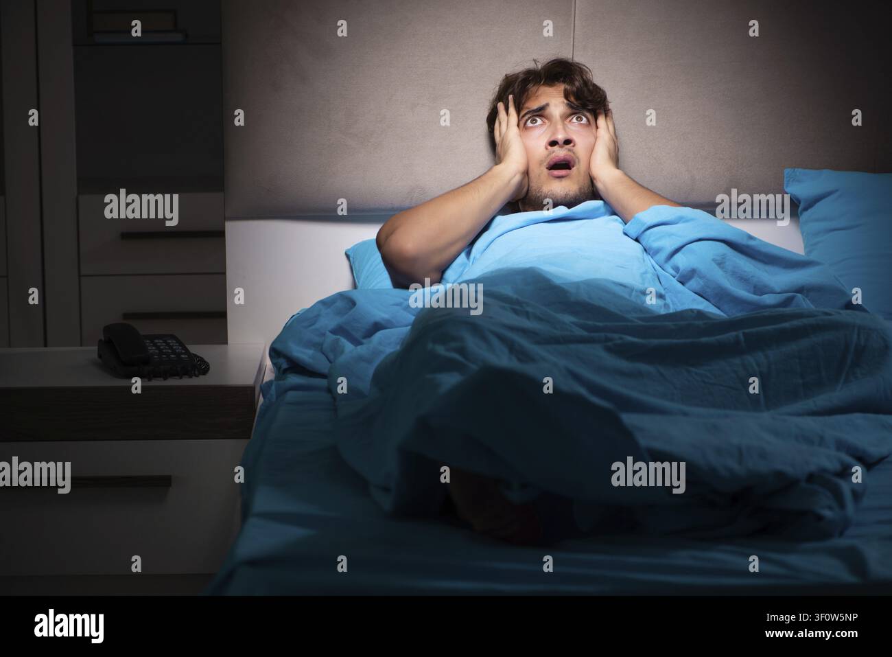 Young man scared in his bed having nightmares Stock Photo