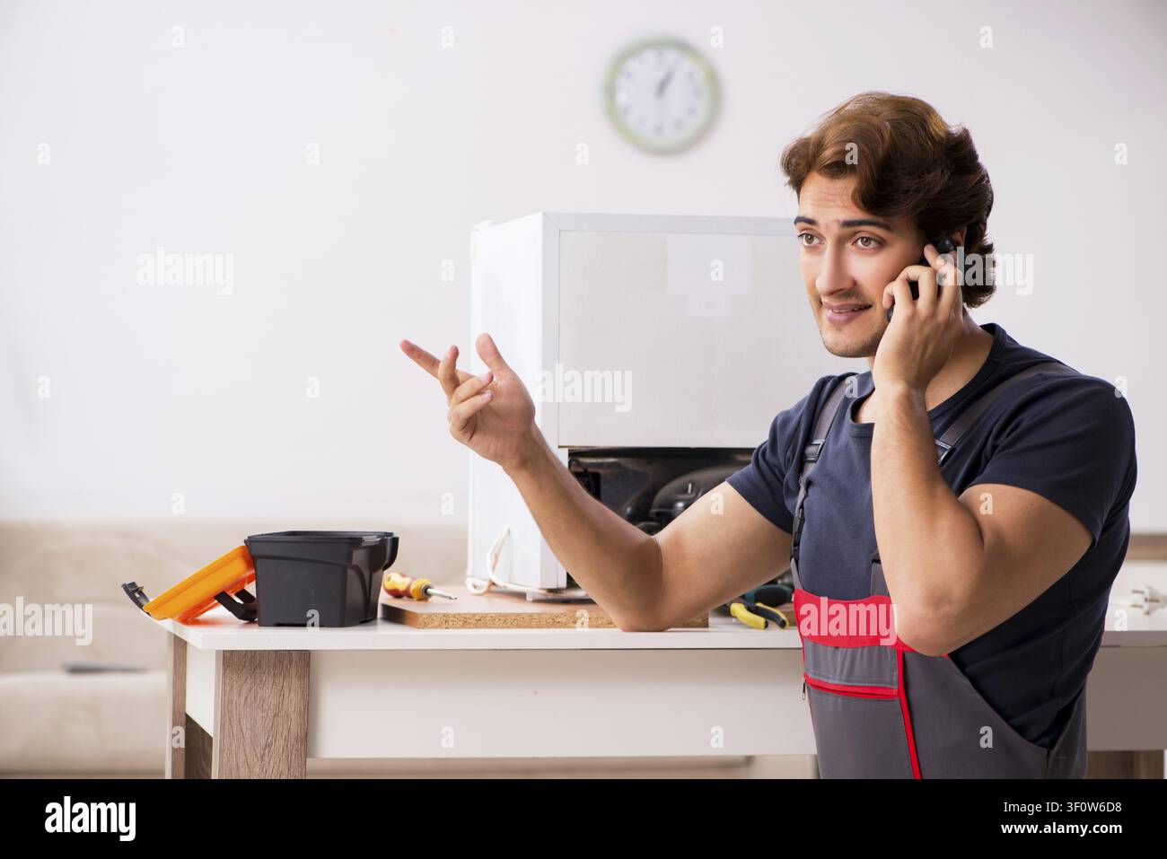 Young handsome contractor repairing fridge Stock Photo