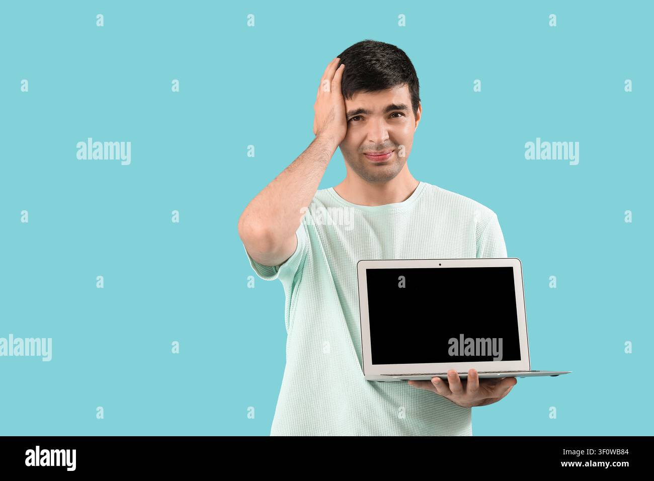Stressed male programmer with laptop on blue background Stock Photo