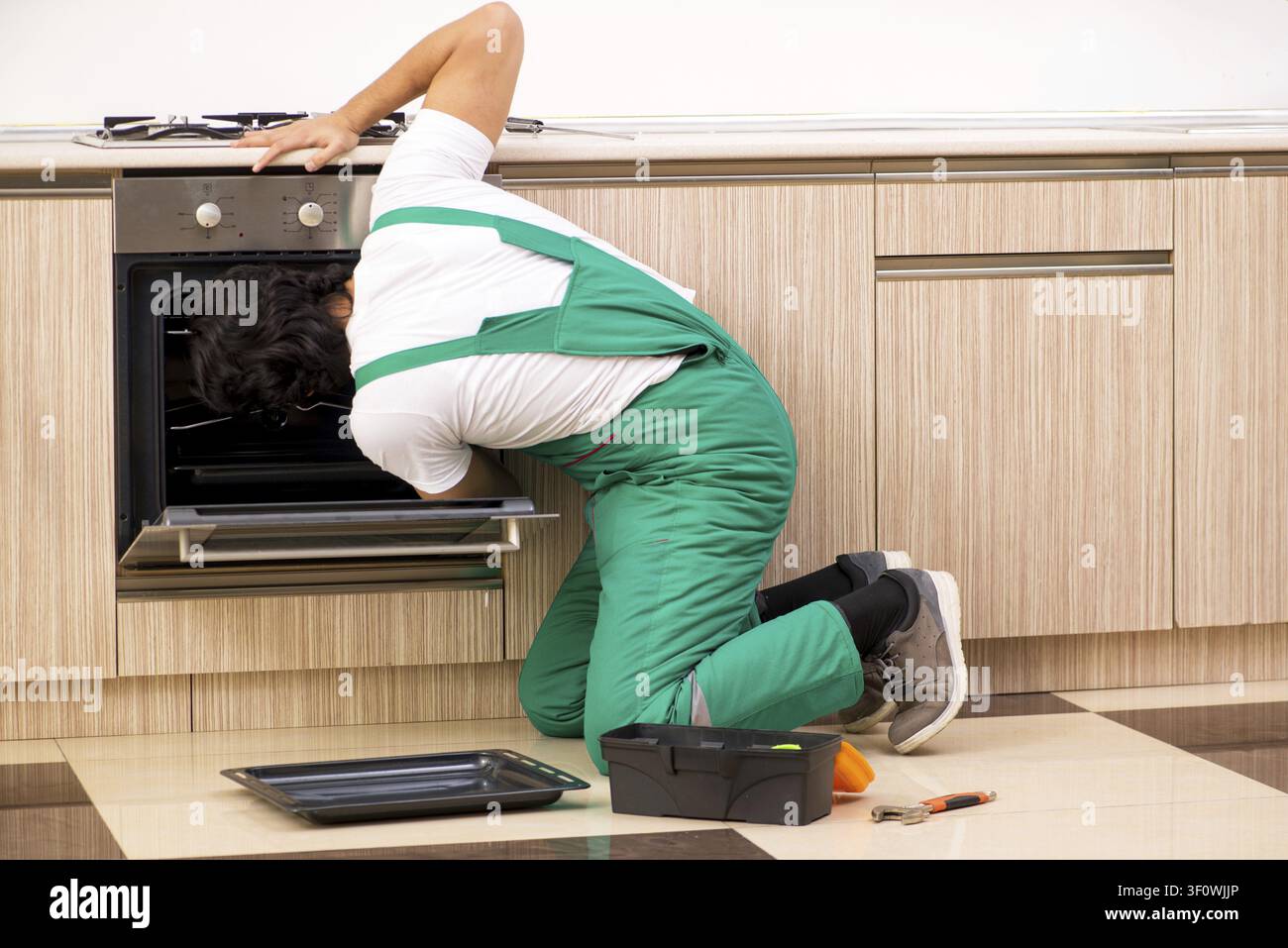 Young contractor repairing oven in kitchen Stock Photo