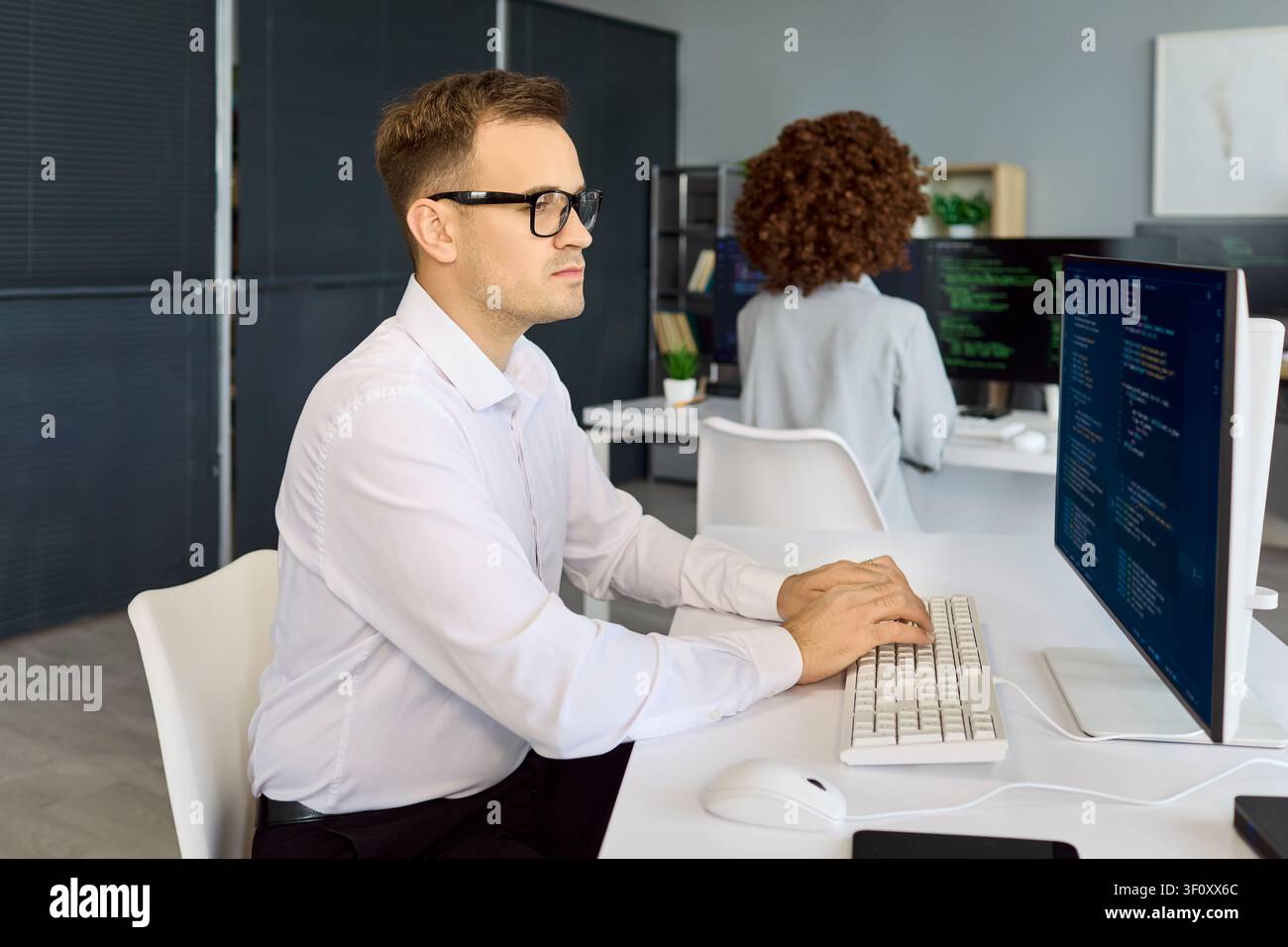 Programmers working on code in tech office with computers screens and teamwork Stock Photo