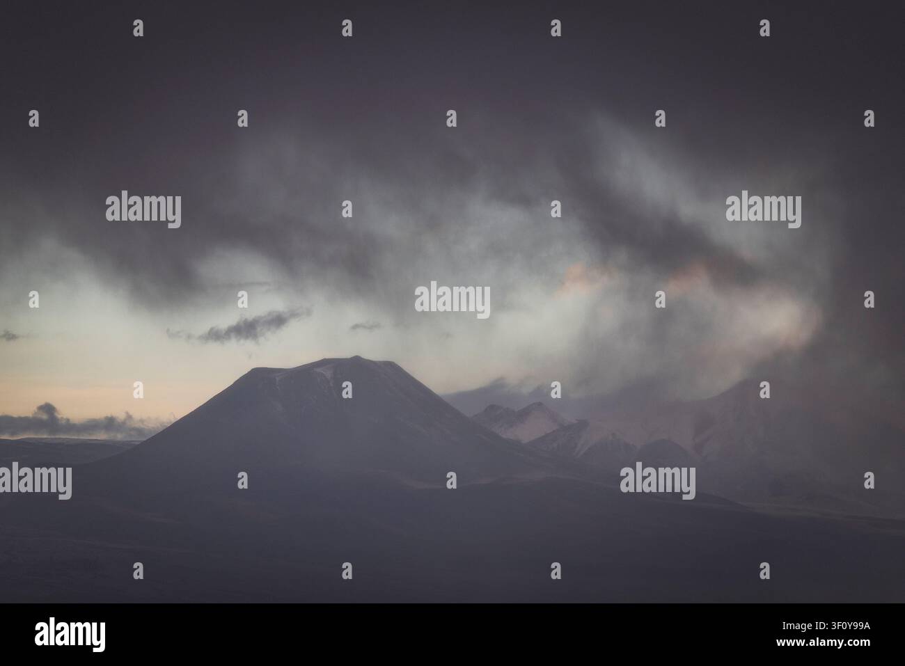 Dramatic storm clouds rolling over mountain peaks Stock Photo