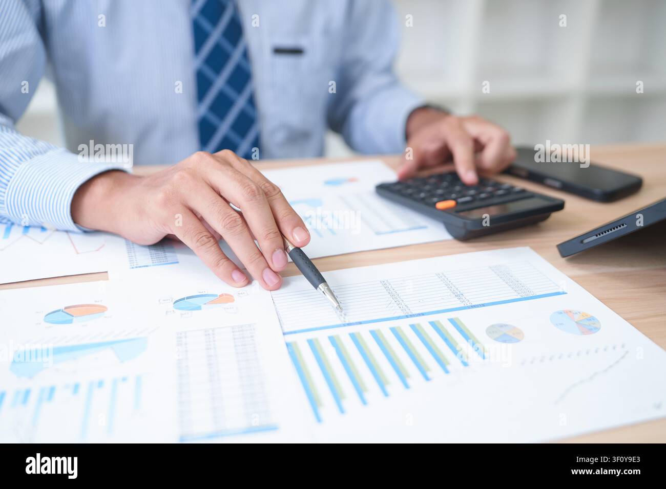 Businessman Analyzing Financial Data with Calculator and Reports Stock Photo