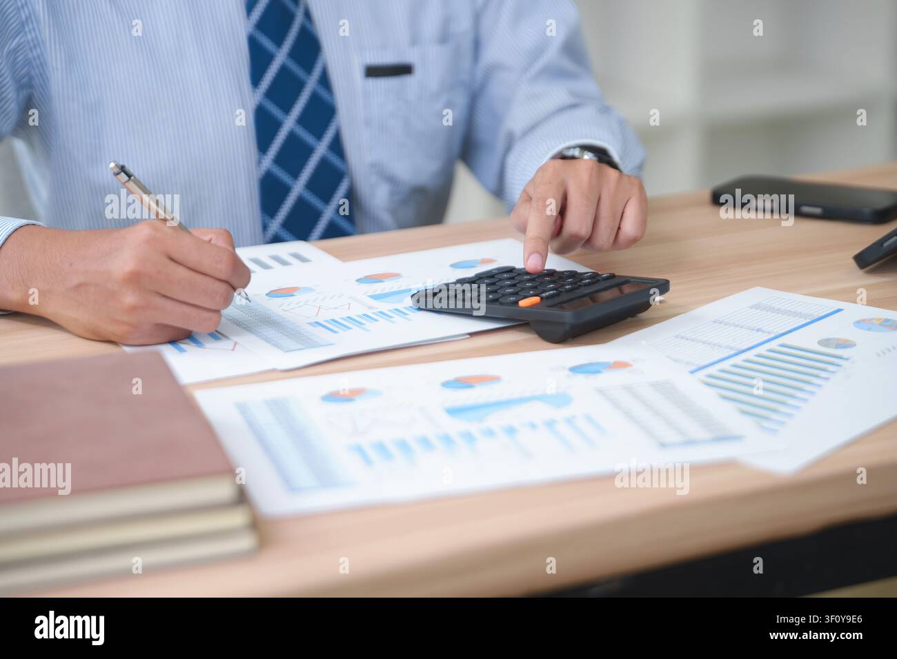 Business Professional Analyzing Financial Reports and Using Calc Stock Photo