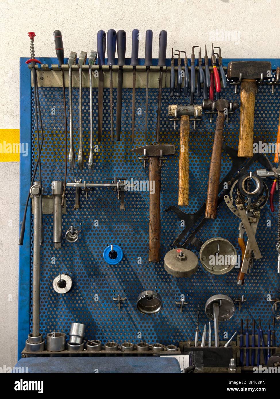 Various mechanic hand tools organized on a blue perforated pegboard Stock Photo