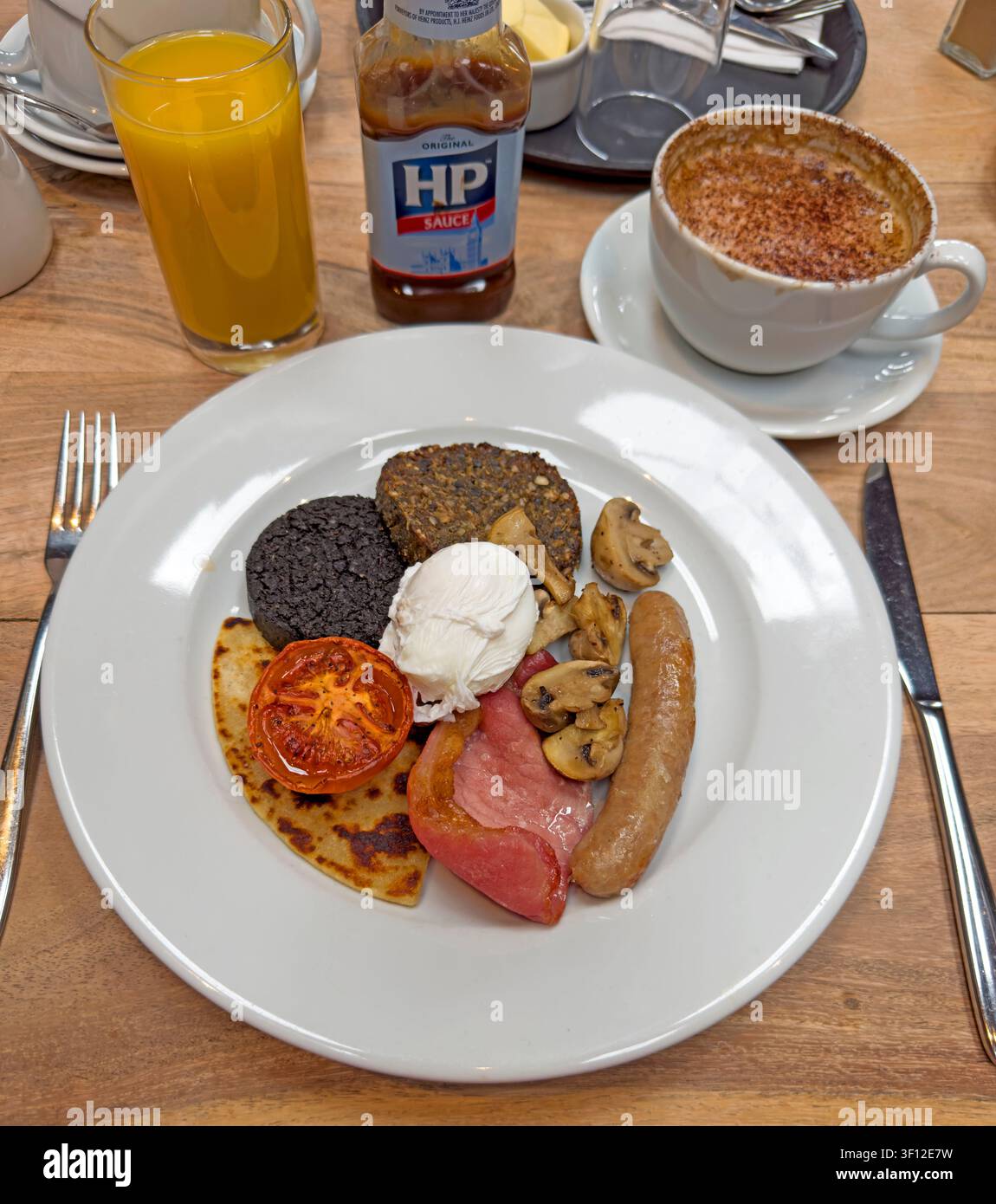 Full Scottish cooked breakfast with eggs, bacon, sausage, mushrooms and toast served at a table in Scotland, UK. Stock Photo