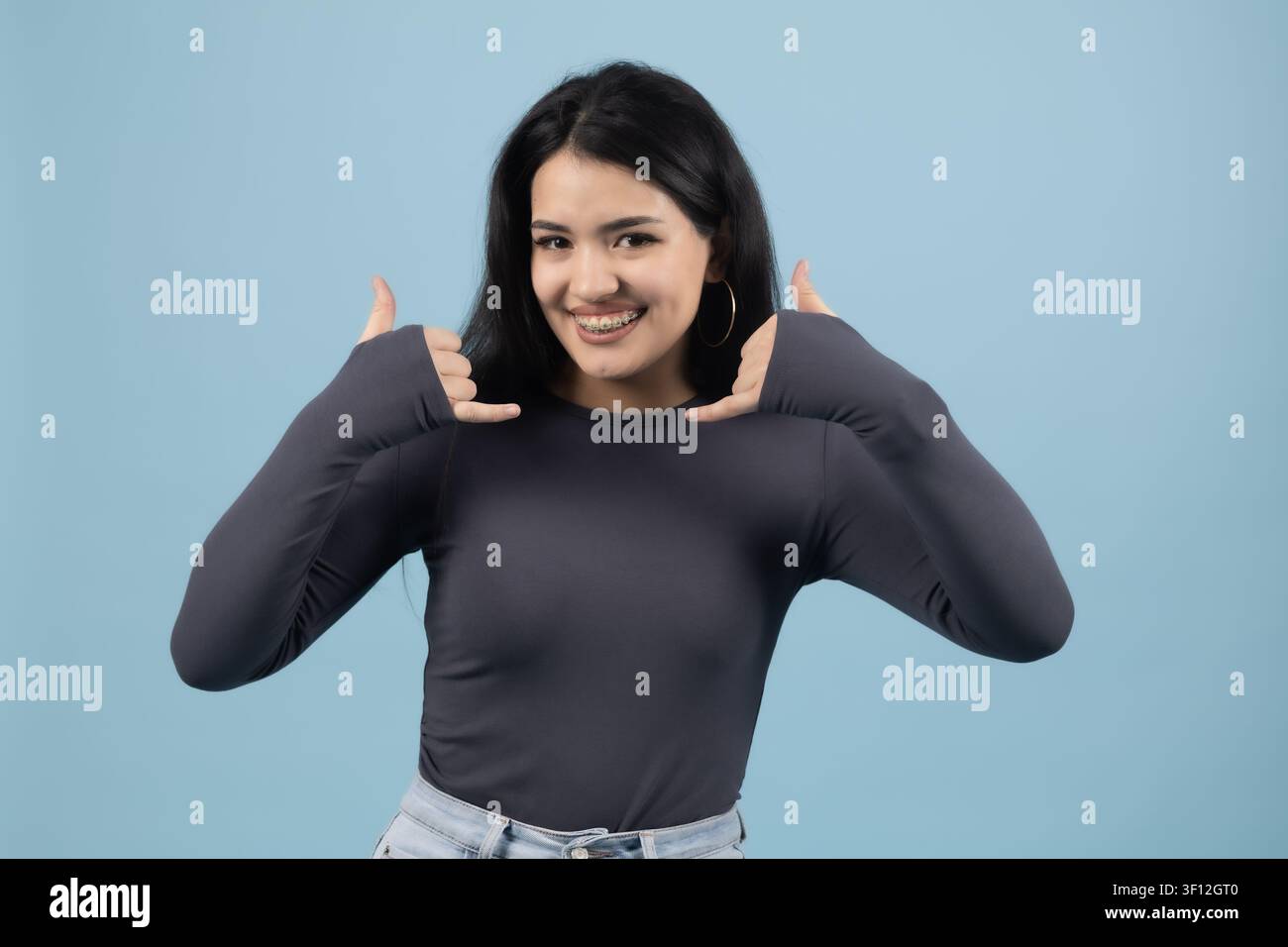 Young woman framing face with hands smiling looking positive Stock Photo