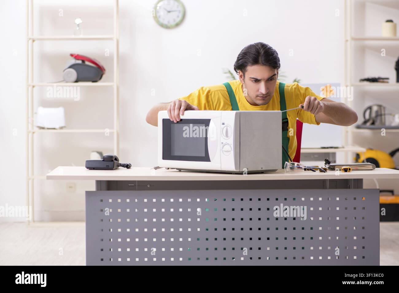 Young repairman repairing microwave in service centre Stock Photo