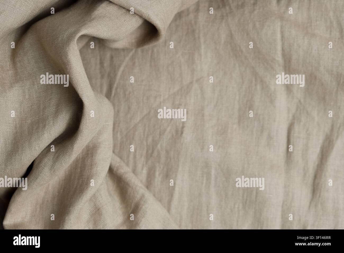 Wrinkled beige natural linen fabric texture background with draperies. Top view Stock Photo