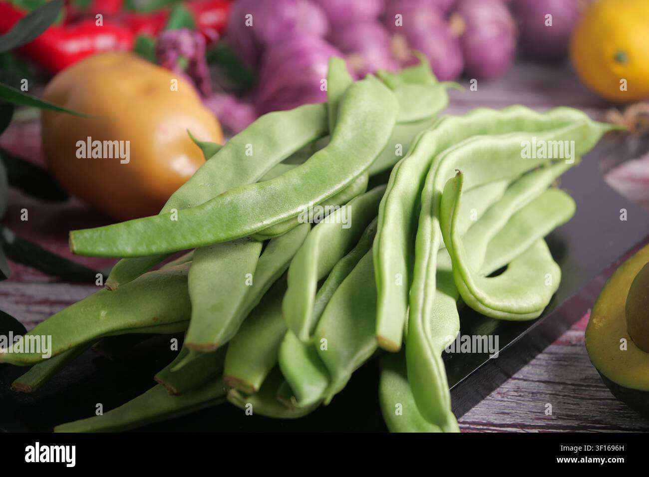 Fresh green beans and vibrant vegetables on a rustic table Stock Photo