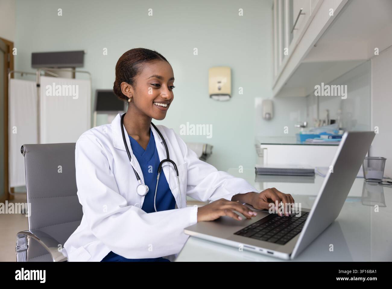 Happy young African general practitioner woman working at computer Stock Photo