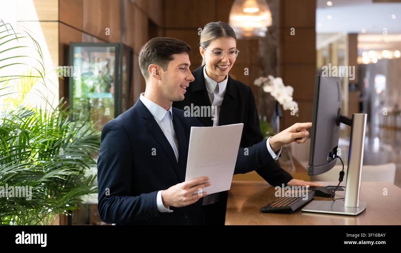 Two colleagues working on paperwork at hotel front desk Stock Photo