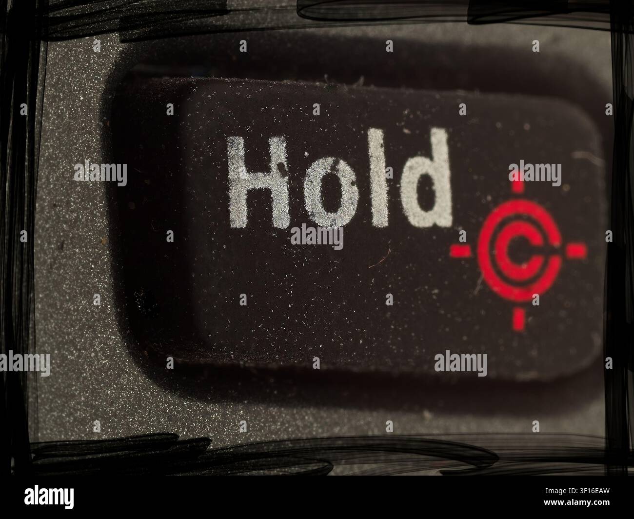 Macro closeup of a rectangular black Hold button with printed white text and a red target icon on a textured device panel Stock Photo