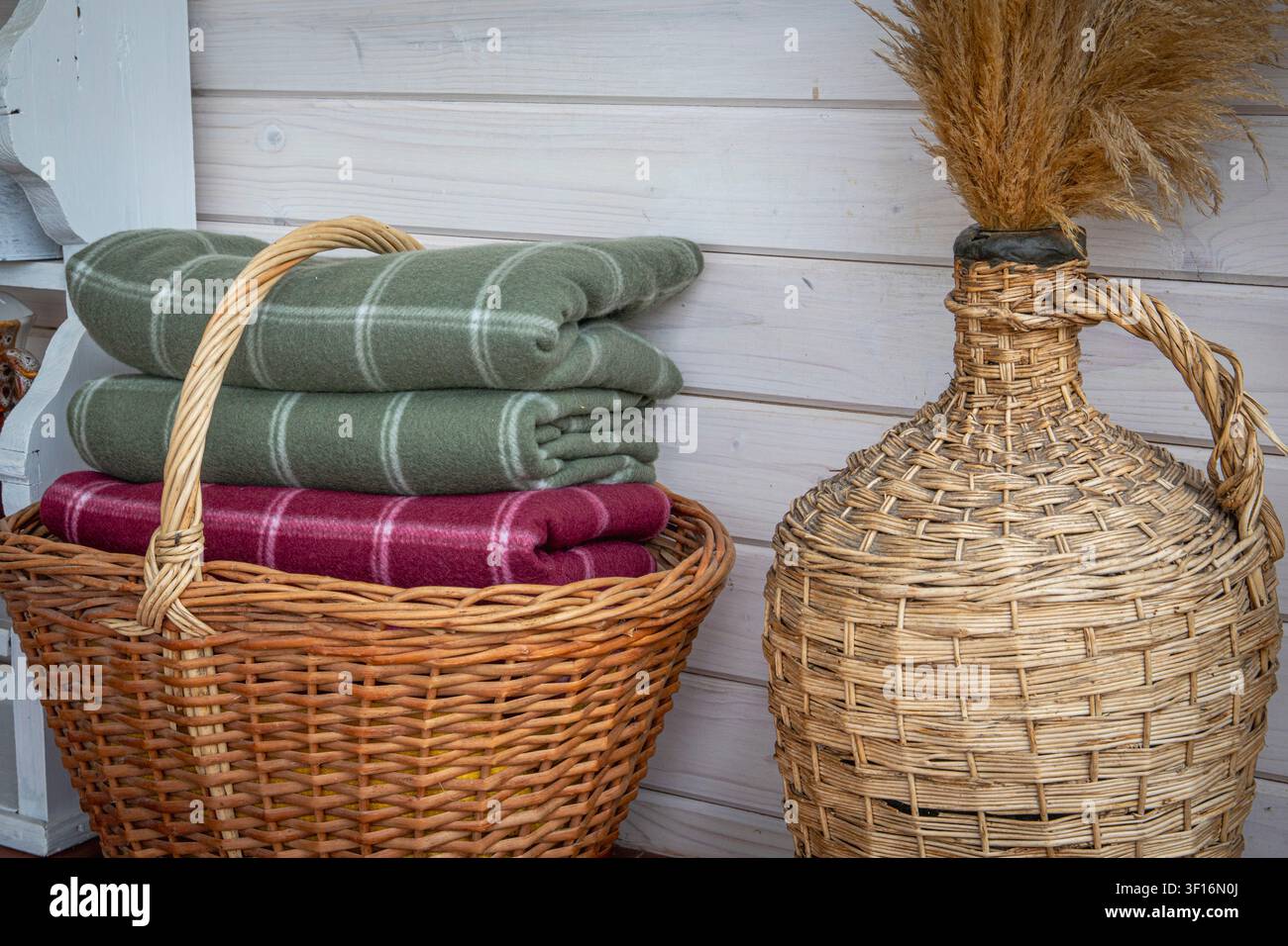 Folded wool blankets in wicker basket creating cozy rustic home interior storage Stock Photo