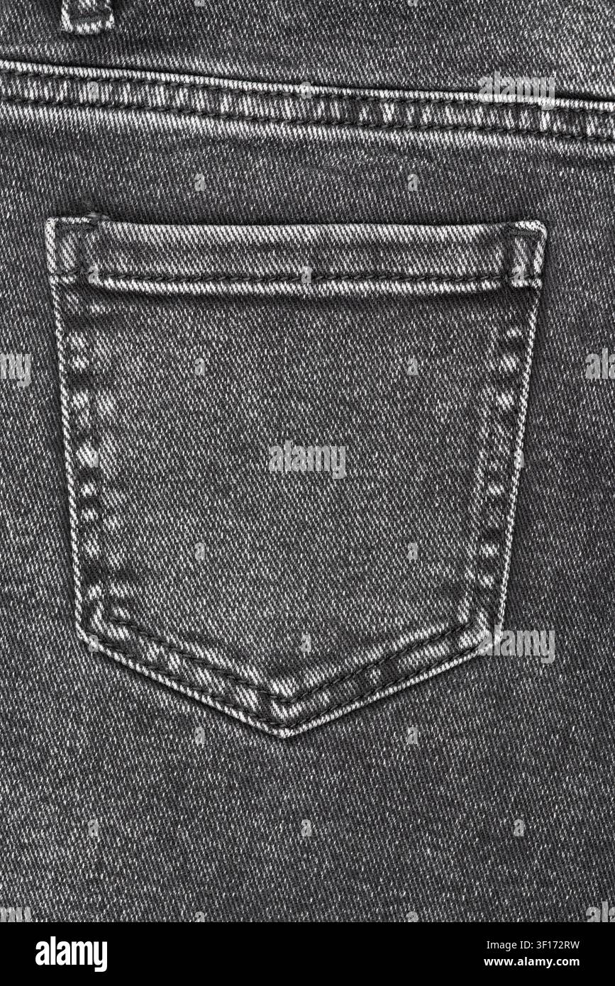 Close up detail shot of back pocket on black denim jeans. Monochrome image highlights fabrics texture, weave and stitching. Great background for fashi Stock Photo