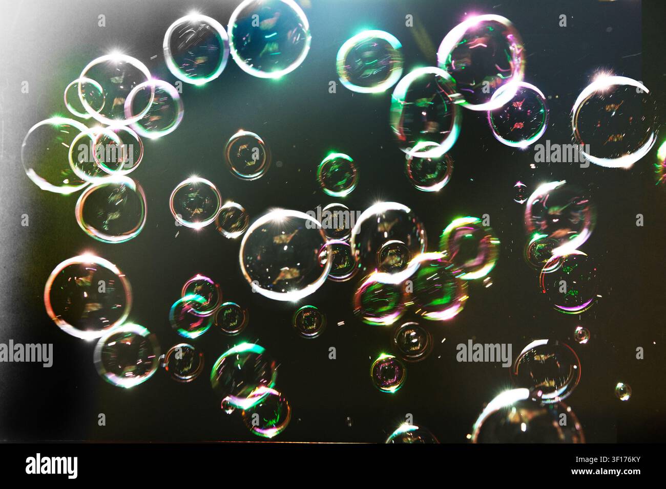 Bubbles floating against a black background, with rainbow colours Stock Photo