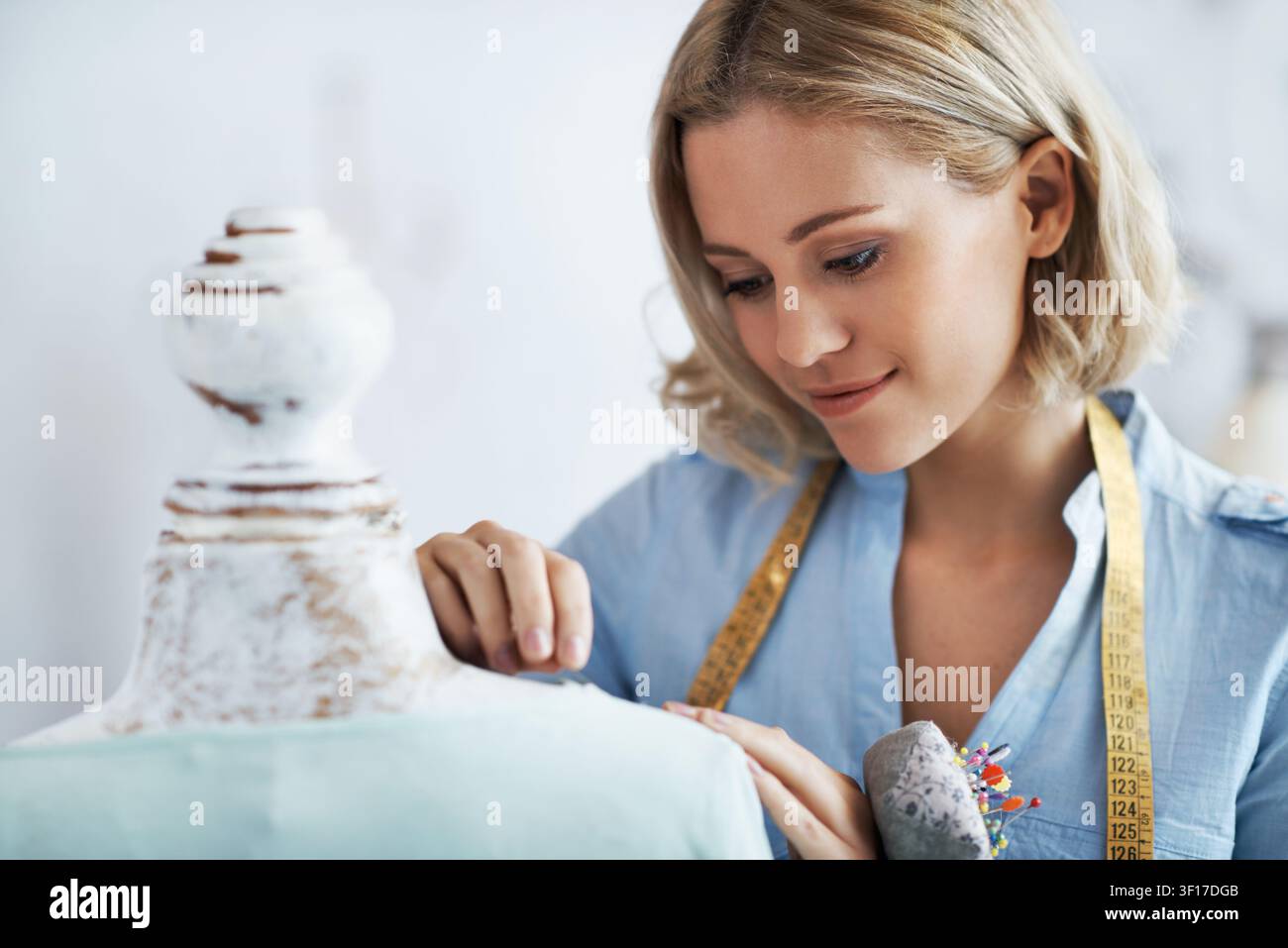 Pin, design and woman with mannequin in startup, adjusting and fashion designer with measuring tape. Checking, seam and happy person with sewing Stock Photo