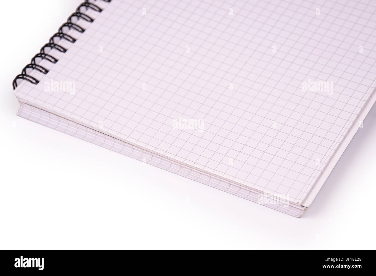 Close-up notebook with spiral binding, grid lines on pages, diagonal composition, clean white background, professional studio lighting, emphasizing te Stock Photo