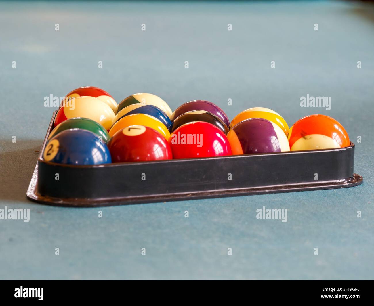 Billiard balls arranged in a triangle rack on a blue felt pool table Stock Photo