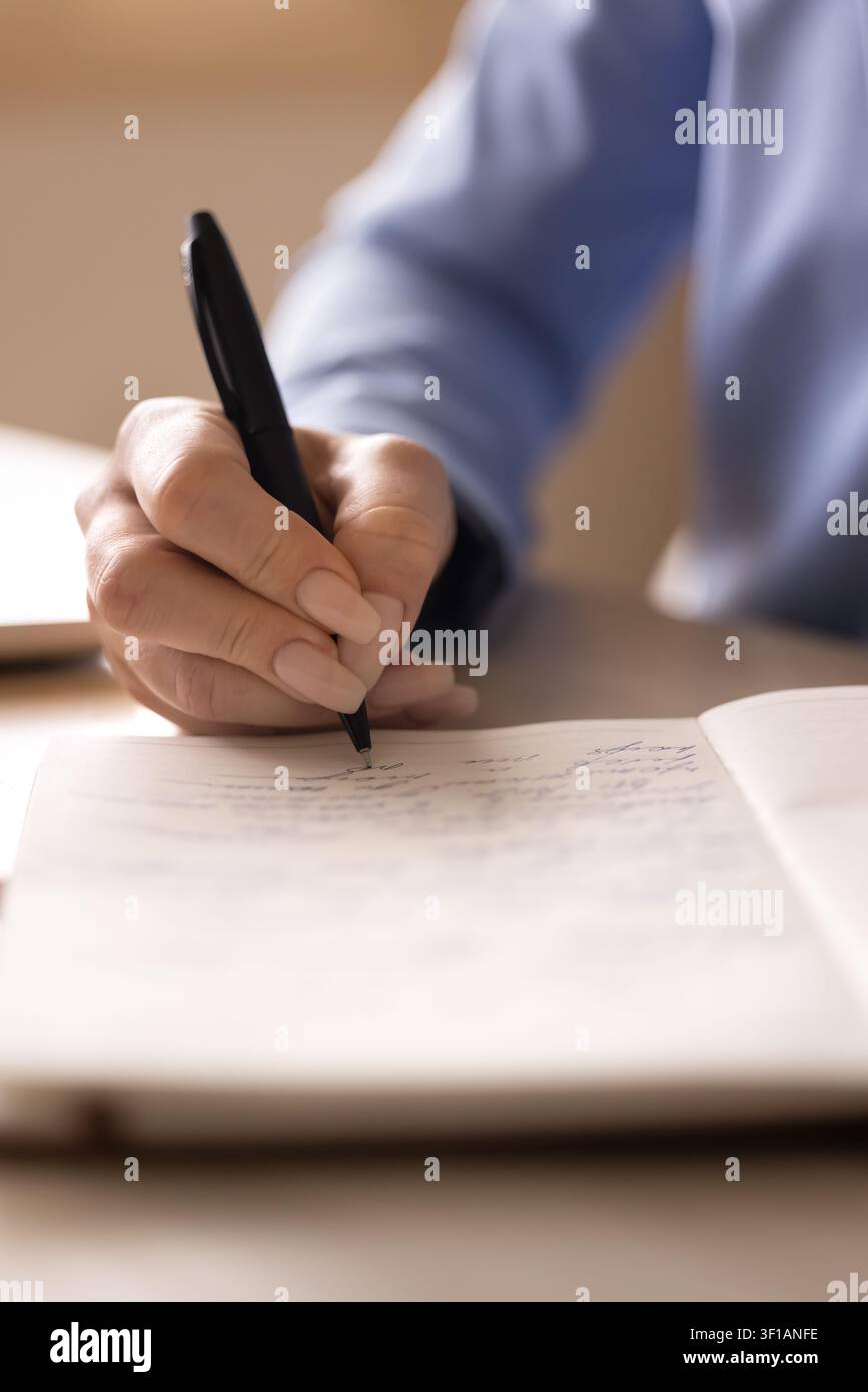 Closeup view female hand writing in notebook Stock Photo