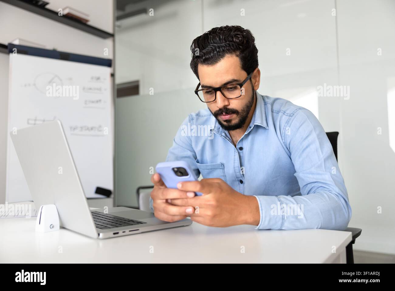 Middle eastern businessman checking smartphone in corporate office Stock Photo