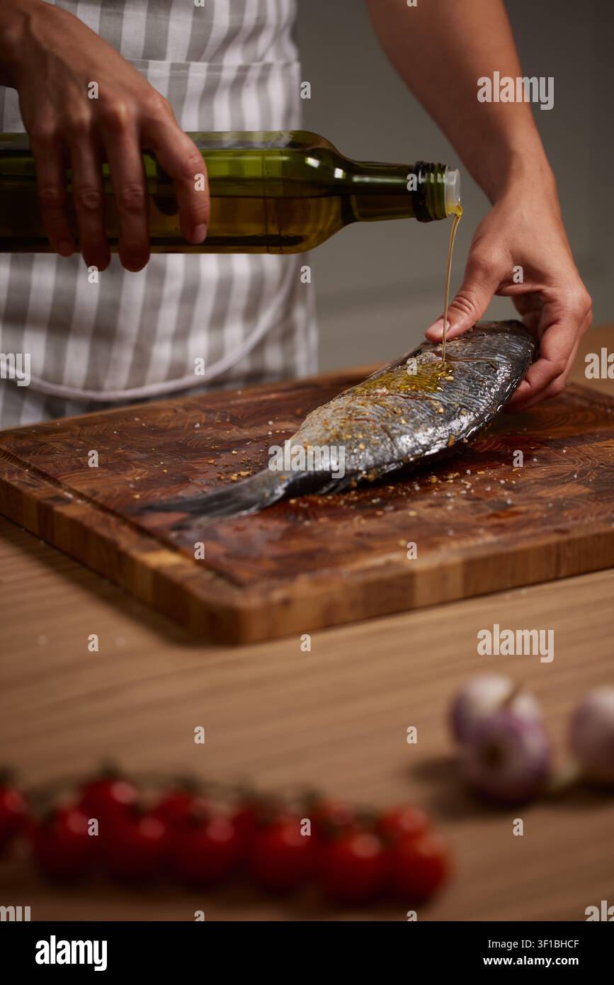 Chef pouring olive oil on fresh fish Stock Photo