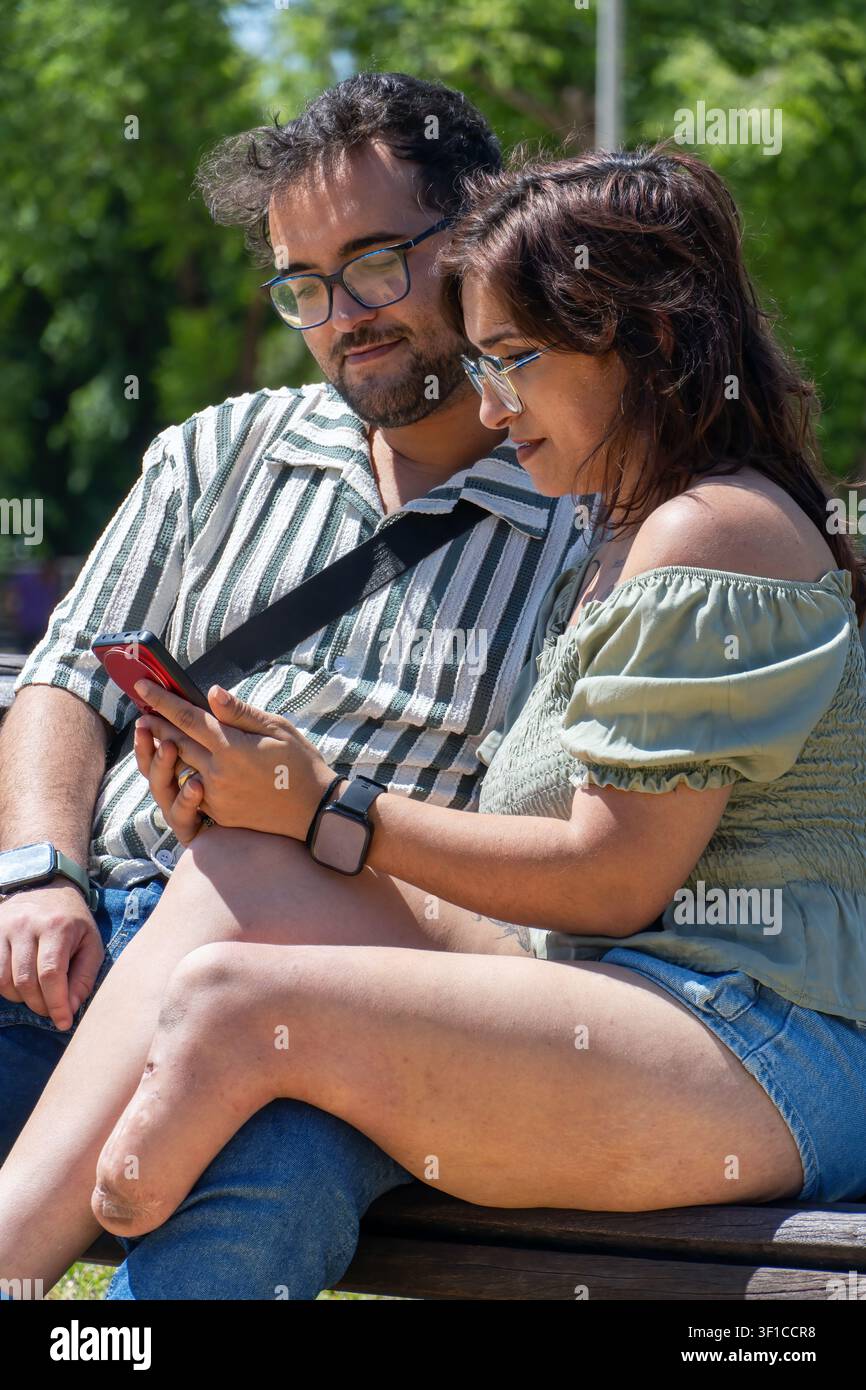 Young couple enjoying shared digital moment in park Stock Photo