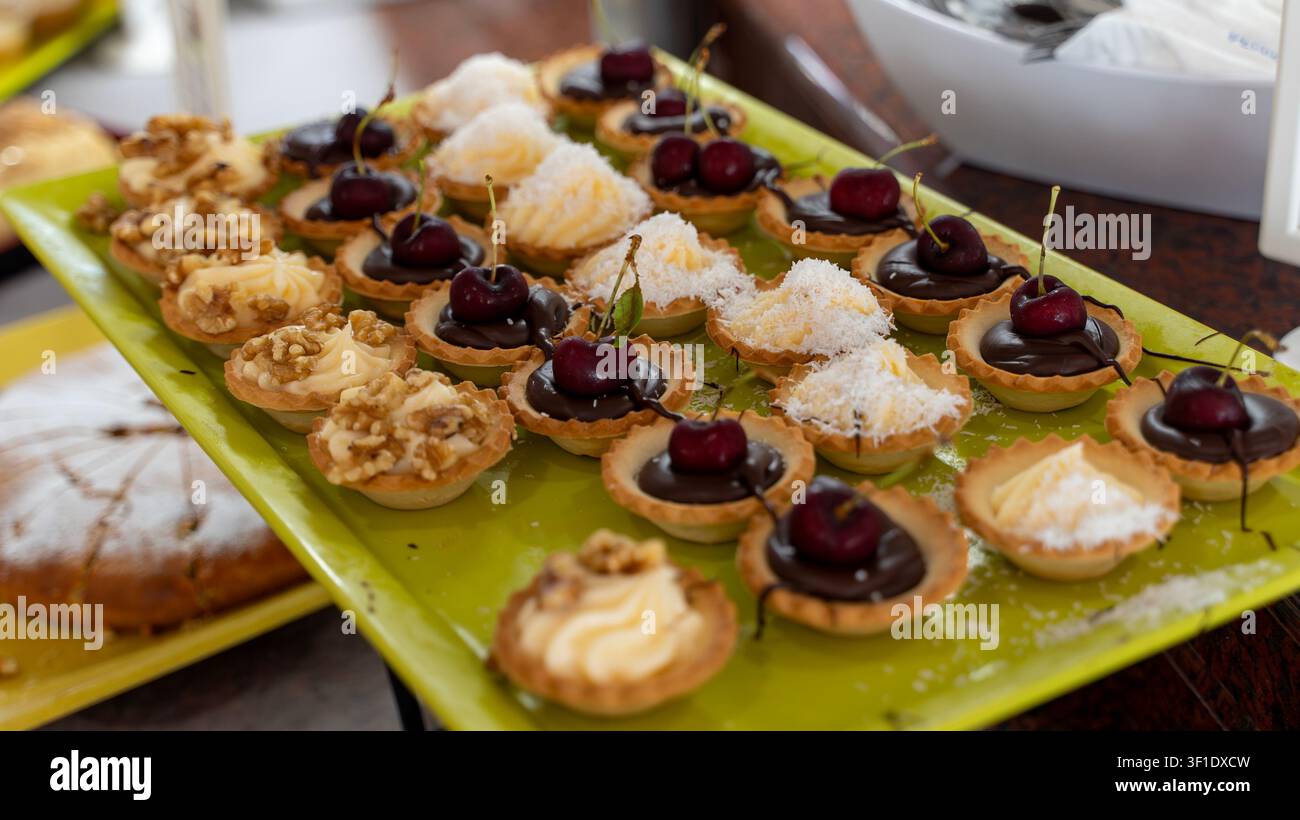 Assorted Mini Dessert Tartlets with Cherries on Buffet Table Stock Photo