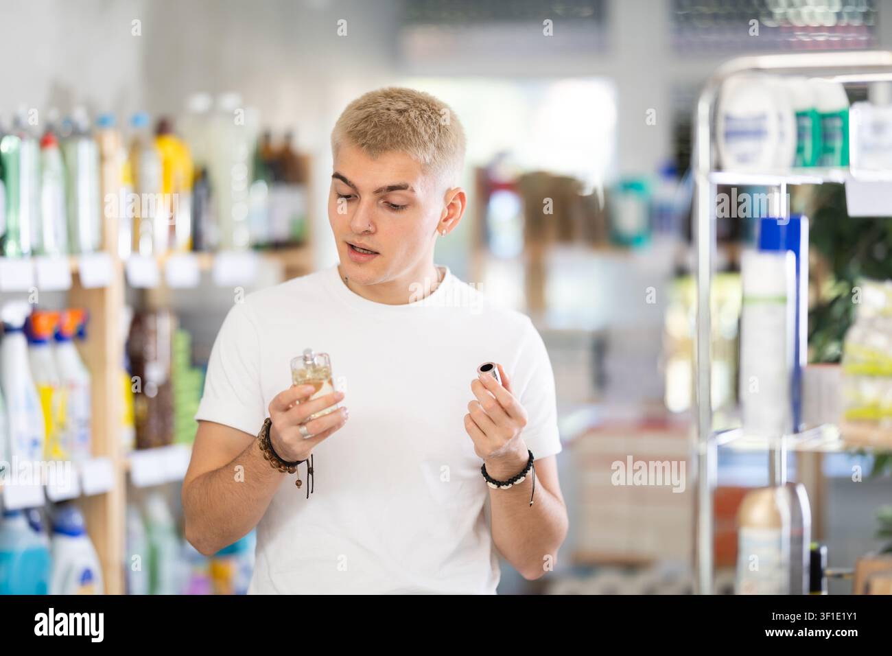 Nice young man customer buying perfume and choosing between two bottle in store Stock Photo