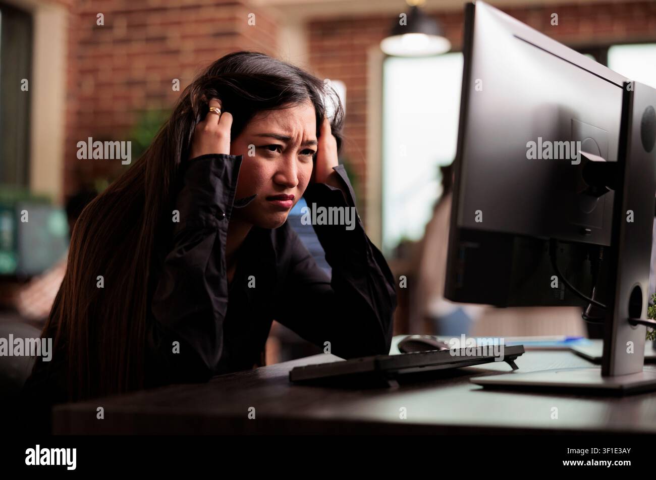Exhausted engineer writes code after overtime while developing cloud computing data, HTML scripts and algorithms on a workplace computer inside an IT office. Stock Photo