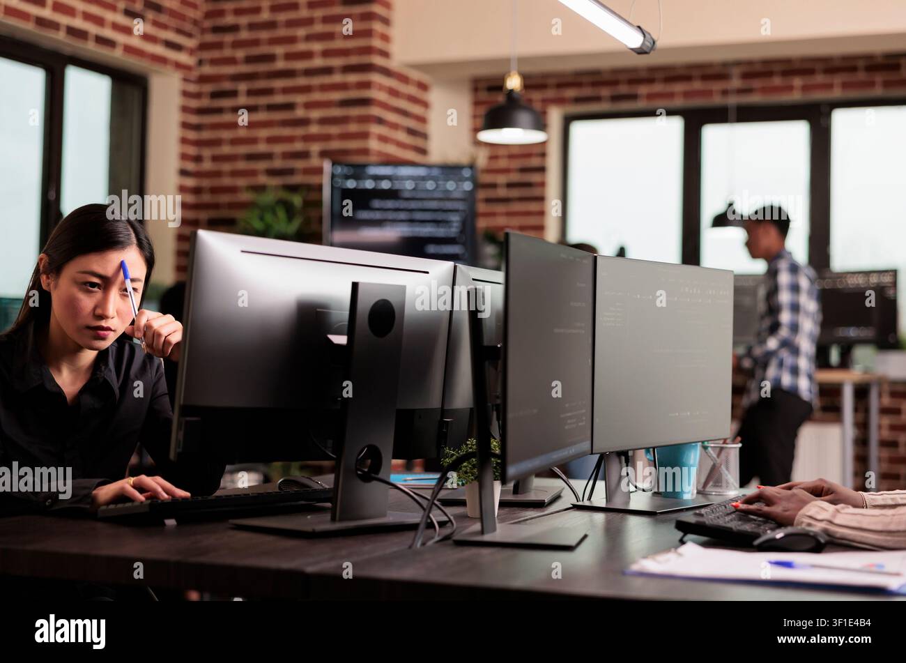 Pensive engineer develops HTML script while developing cloud computing data, HTML scripts and algorithms on a workplace computer inside an IT office. Stock Photo