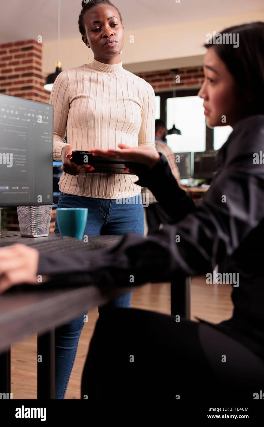 Software development team reviewing HTML code together in a programming workspace, connecting source code, database logic and collaborative development for a technology project. Stock Photo