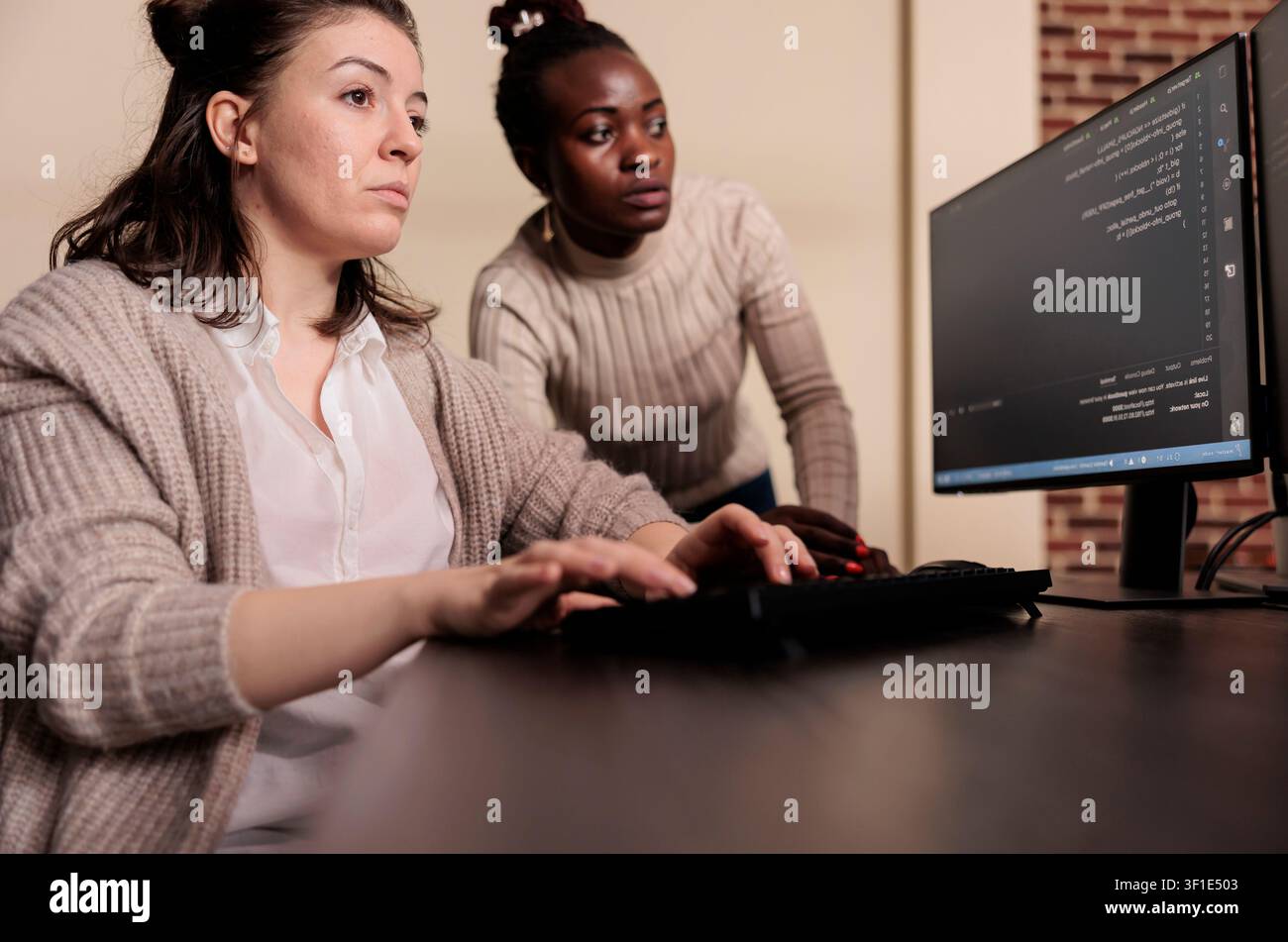 Diverse engineering team discusses programming in an IT development agency while a developer compiles app language and server algorithms. Stock Photo
