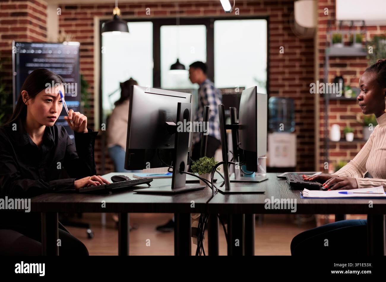 Pensive Asian programmer brainstorms ideas while developing HTML script and thinking about database server logic inside an IT agency office. Stock Photo