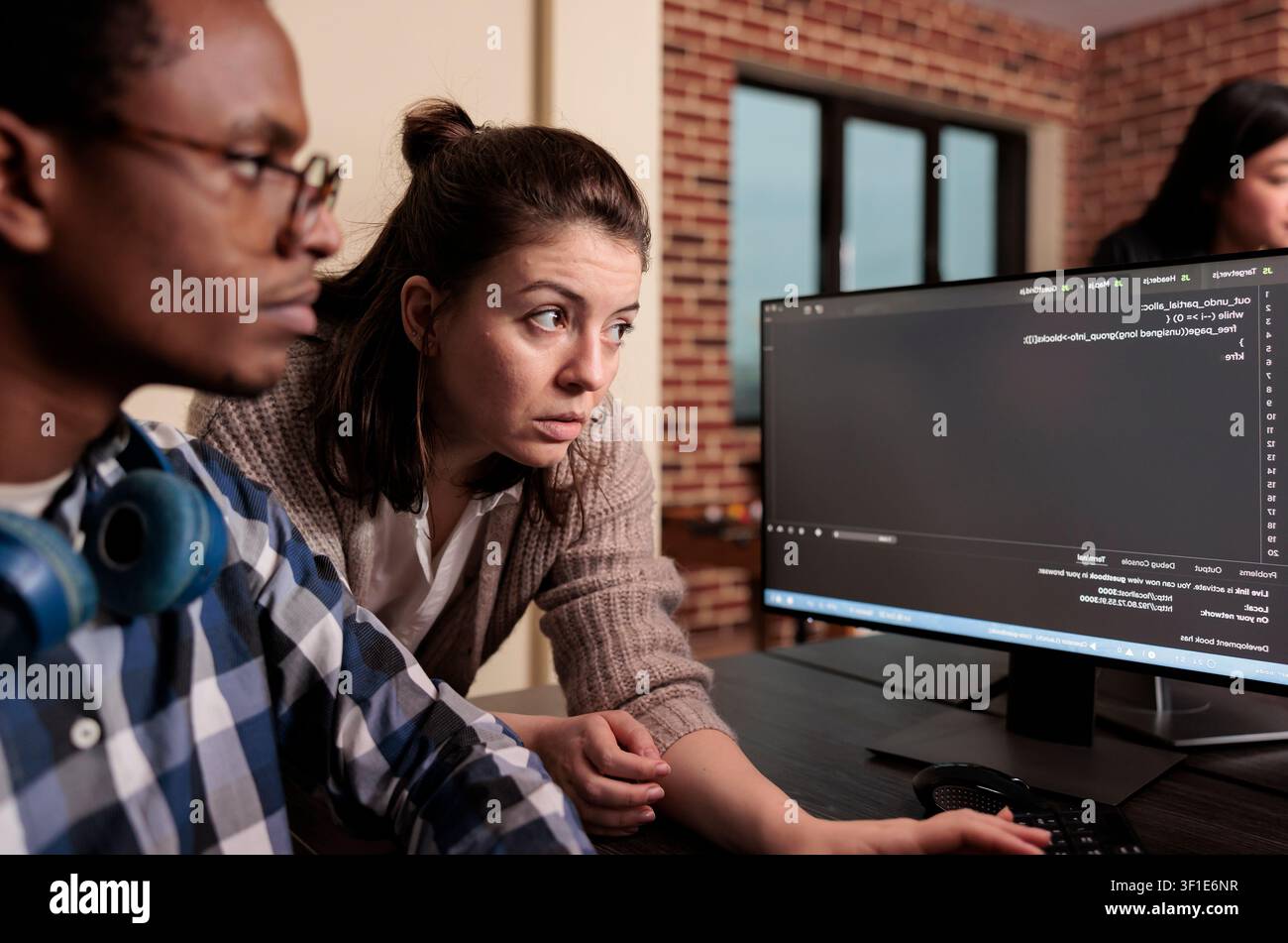 Tech engineer asking app designer for help with html code, pointing at database script on terminal window, Team of programming engineers working on app developing program in it agency. Stock Photo