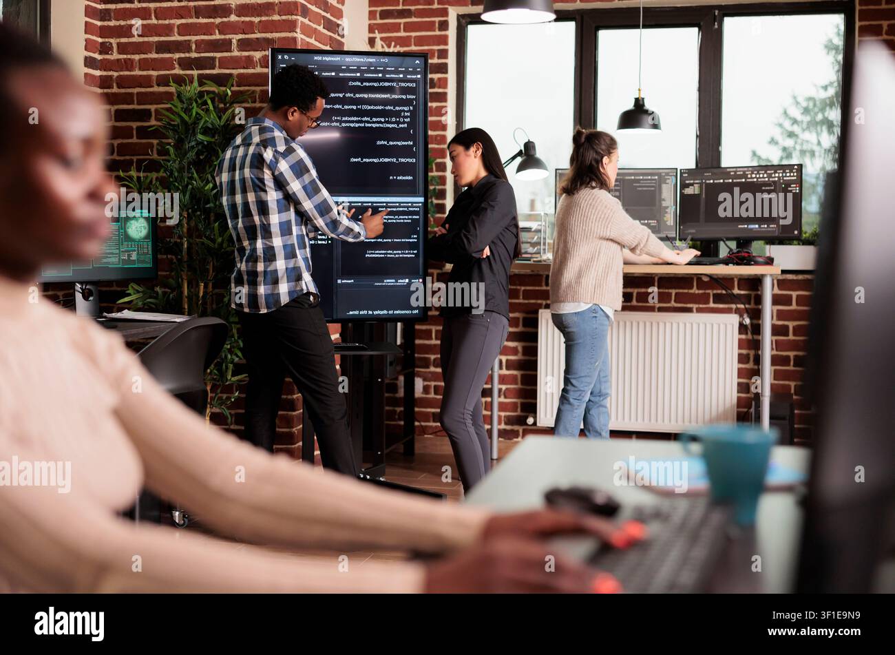 Diverse tech engineers use binary code to program firewall encryption and develop network security software on a shared server system. Stock Photo