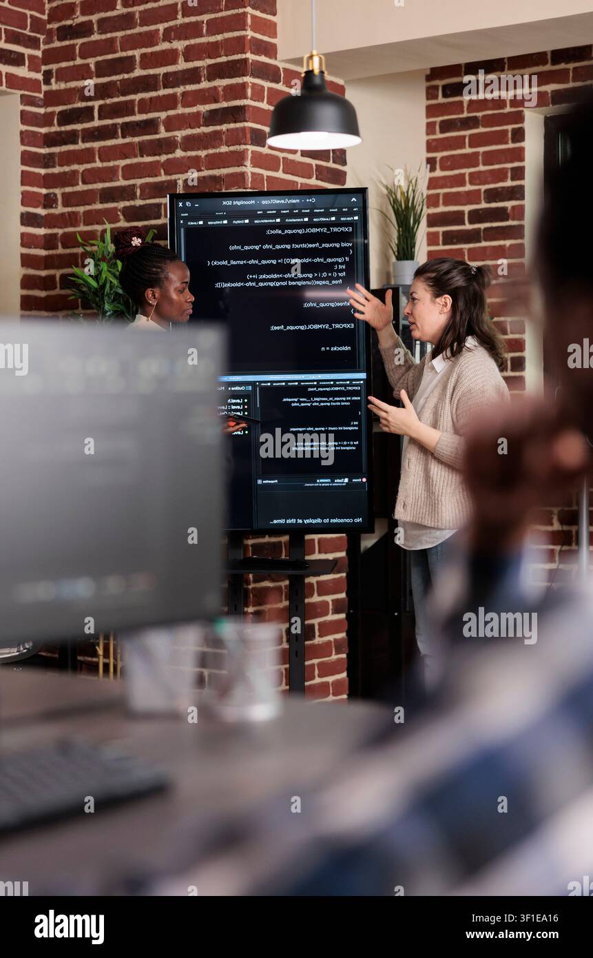Multiethnic developers discuss rising system security breaches while working on storage problems and artificial intelligence solutions. Stock Photo