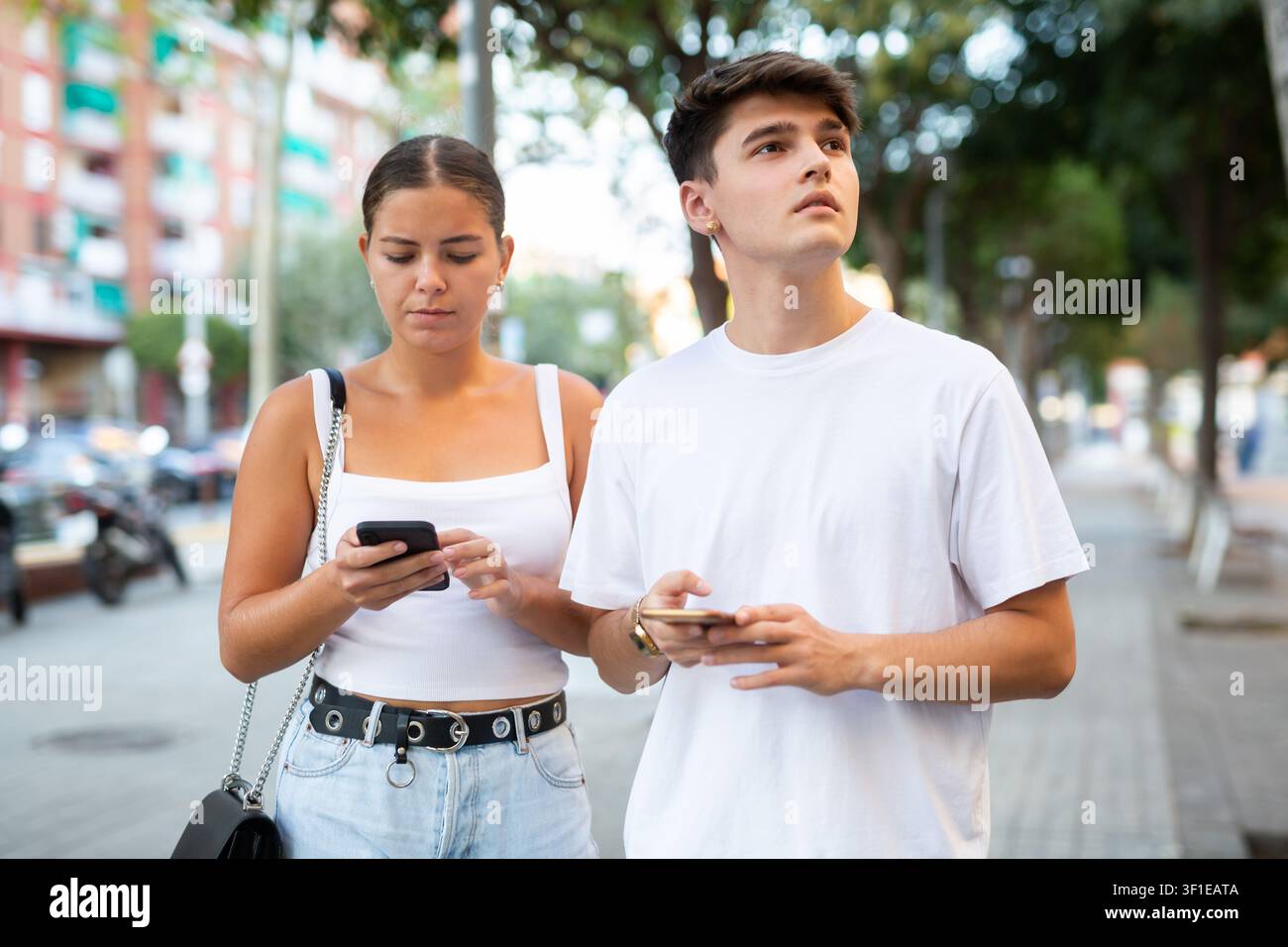 Young couple using smartphones while walking Stock Photo