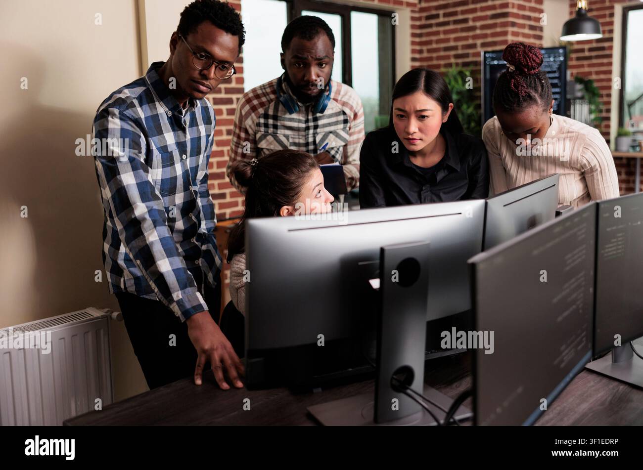 Cyber security team develops software processing algorithm during a indoor setting moment involving african american, brick wall and multiethnic cyber Stock Photo