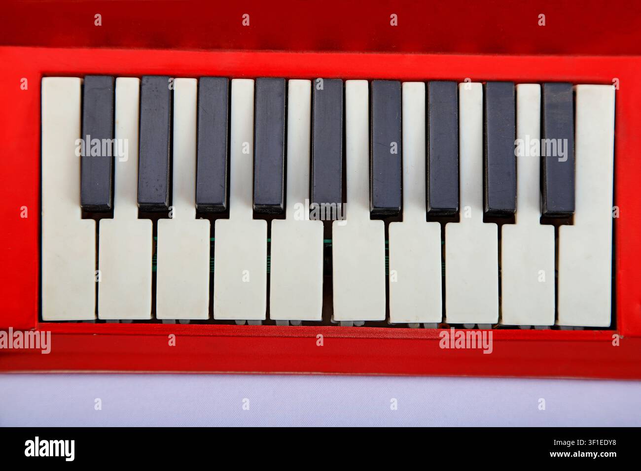 A detailed close-up shot of the black and white keys on a compact, red-framed electronic keyboard or synthesizer. The clean, retro-inspired design and Stock Photo