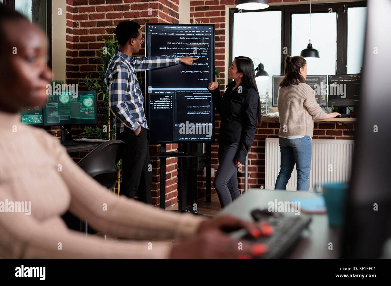 Backend network developer explains application code to a coworker as the team builds security layers for stable software functionality. Stock Photo