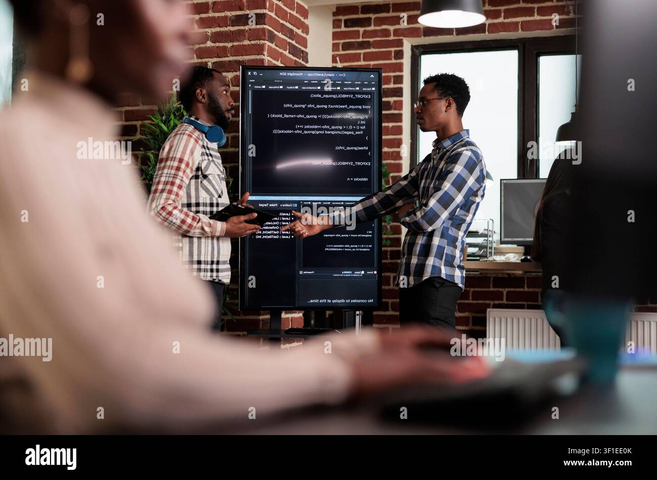 Software developer points out a cloud database algorithm error while discussing corrupted encrypted files and cyber security with a colleague. Stock Photo