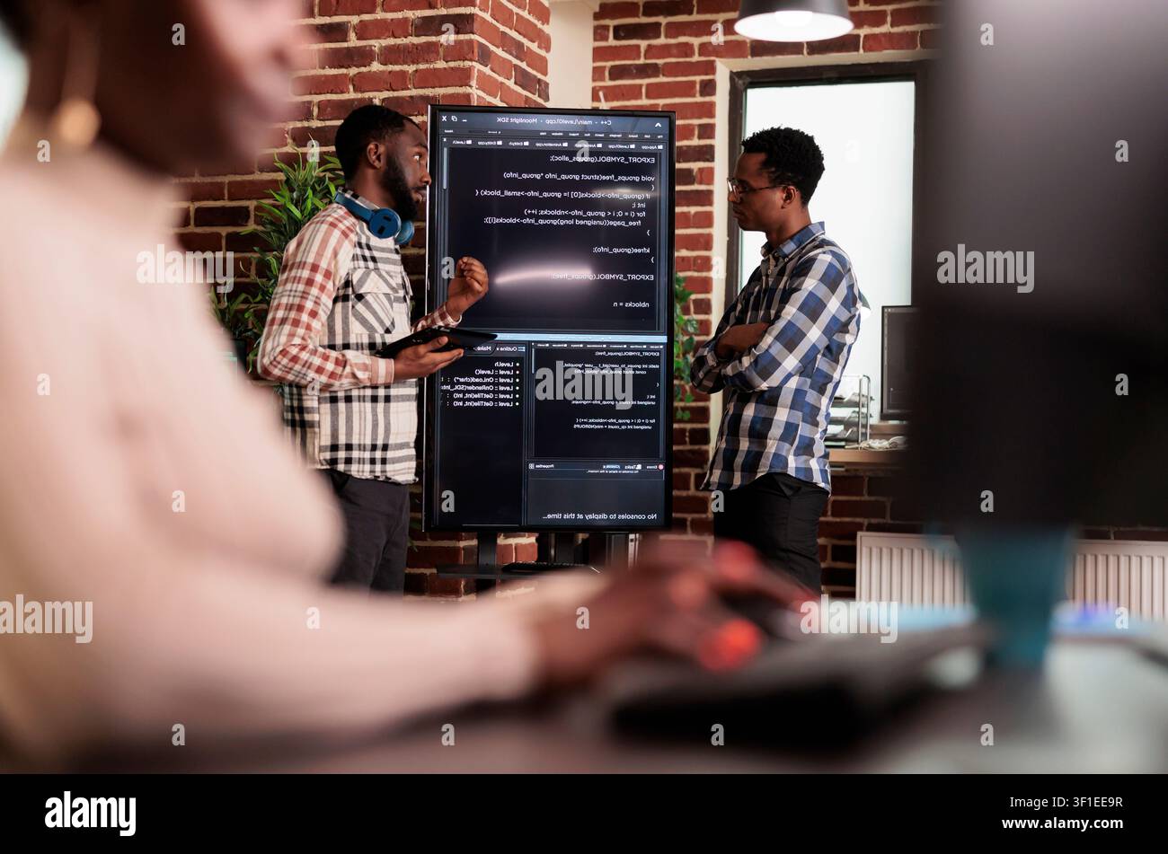 Programming engineers analyzing code on screens with programmers, screens and infrastructure details supporting software development and system monitoring. Stock Photo