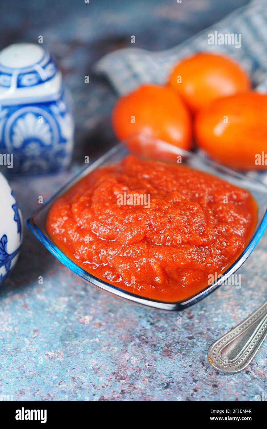 Fresh tomato sauce and oranges on a kitchen table Stock Photo