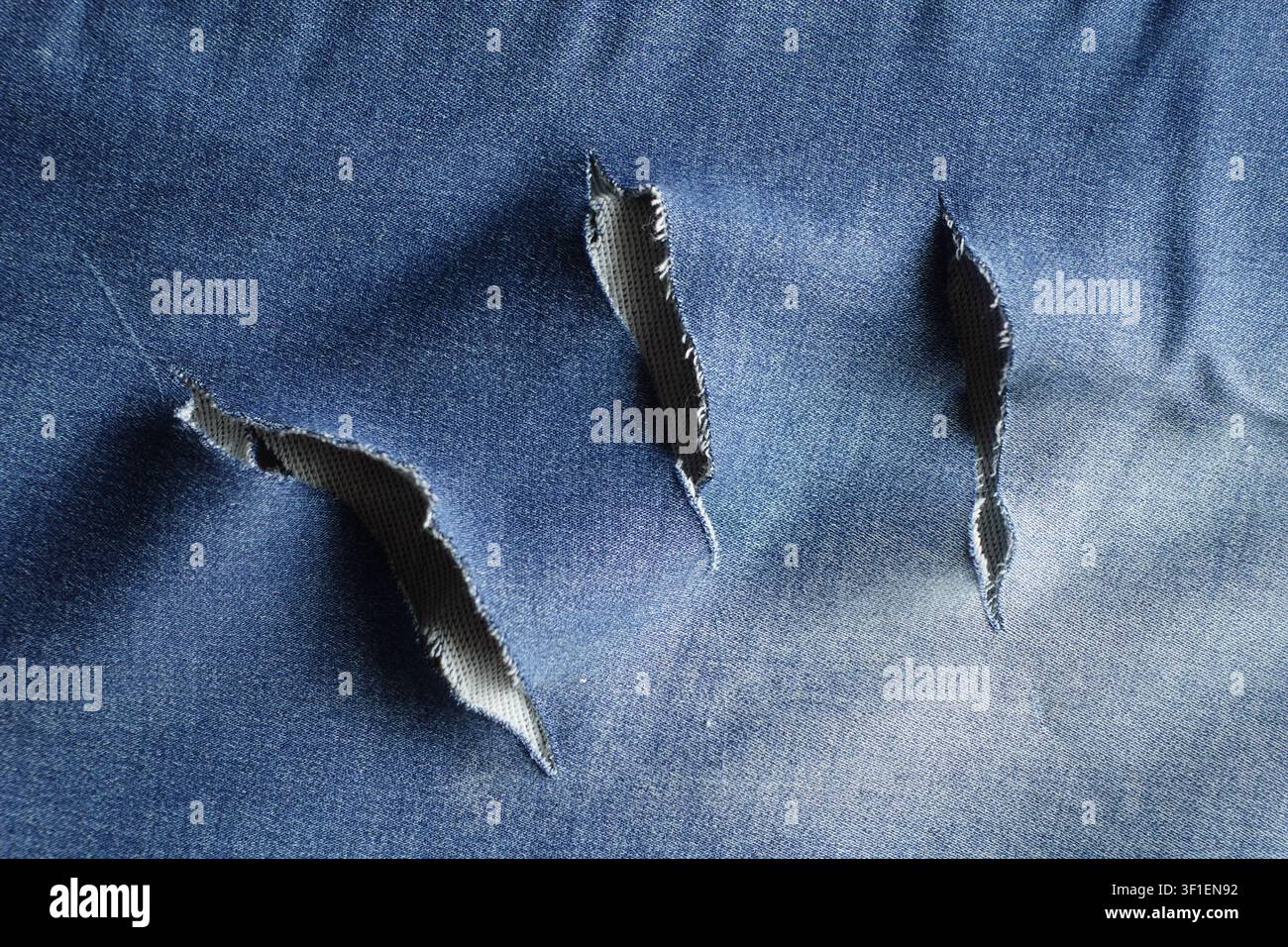 Torn fabric showing damage in blue denim material Stock Photo